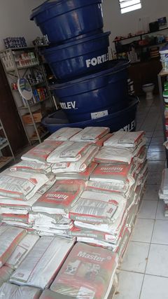 Caixas d’água azuis e sacos de argamassa no interior da loja.