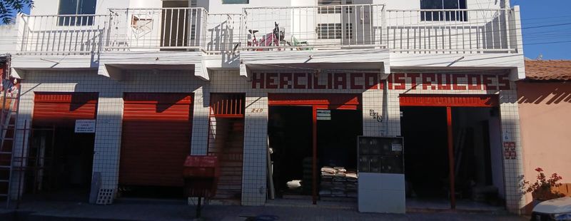 Fachada da loja com revestimento claro, letreiro e entradas vermelhas.