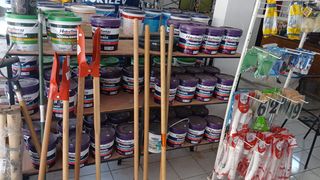Latas de tinta, ferramentas de cabo longo e acessórios de pintura.